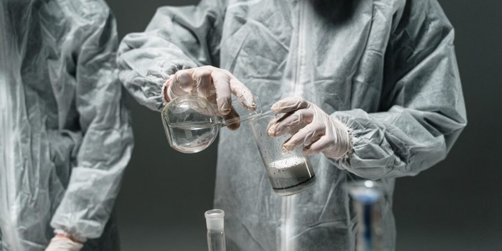 Laboratory technician in a protective suit with glassware