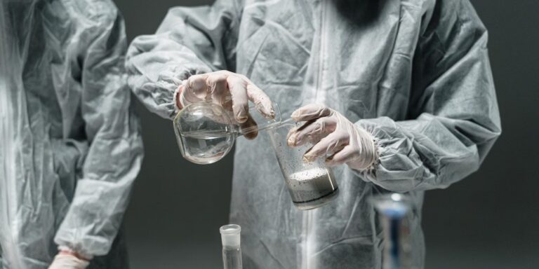 Laboratory technician in a protective suit with glassware